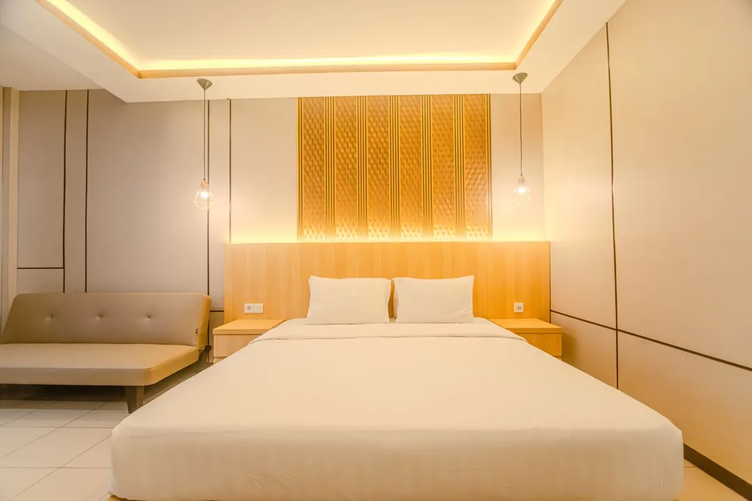 Kamar Executive Five Style — king bed dengan sofa dan pencahayaan hangat
